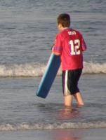 A boy boogie boarding in his clothes